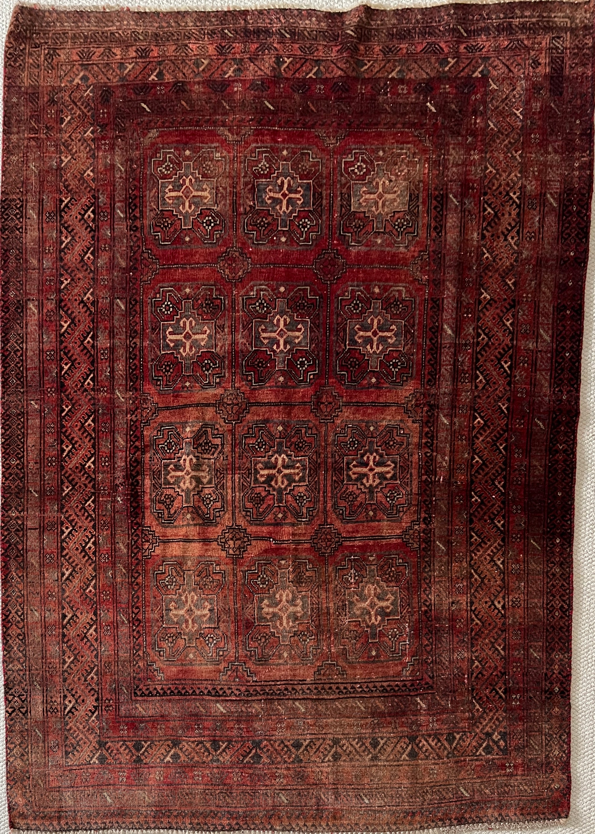 Vintage Turkoman wool area rug, 4x6, full image with varying shades of red and rust in a geometric pattern with cream, charcoal and dark brown accents.