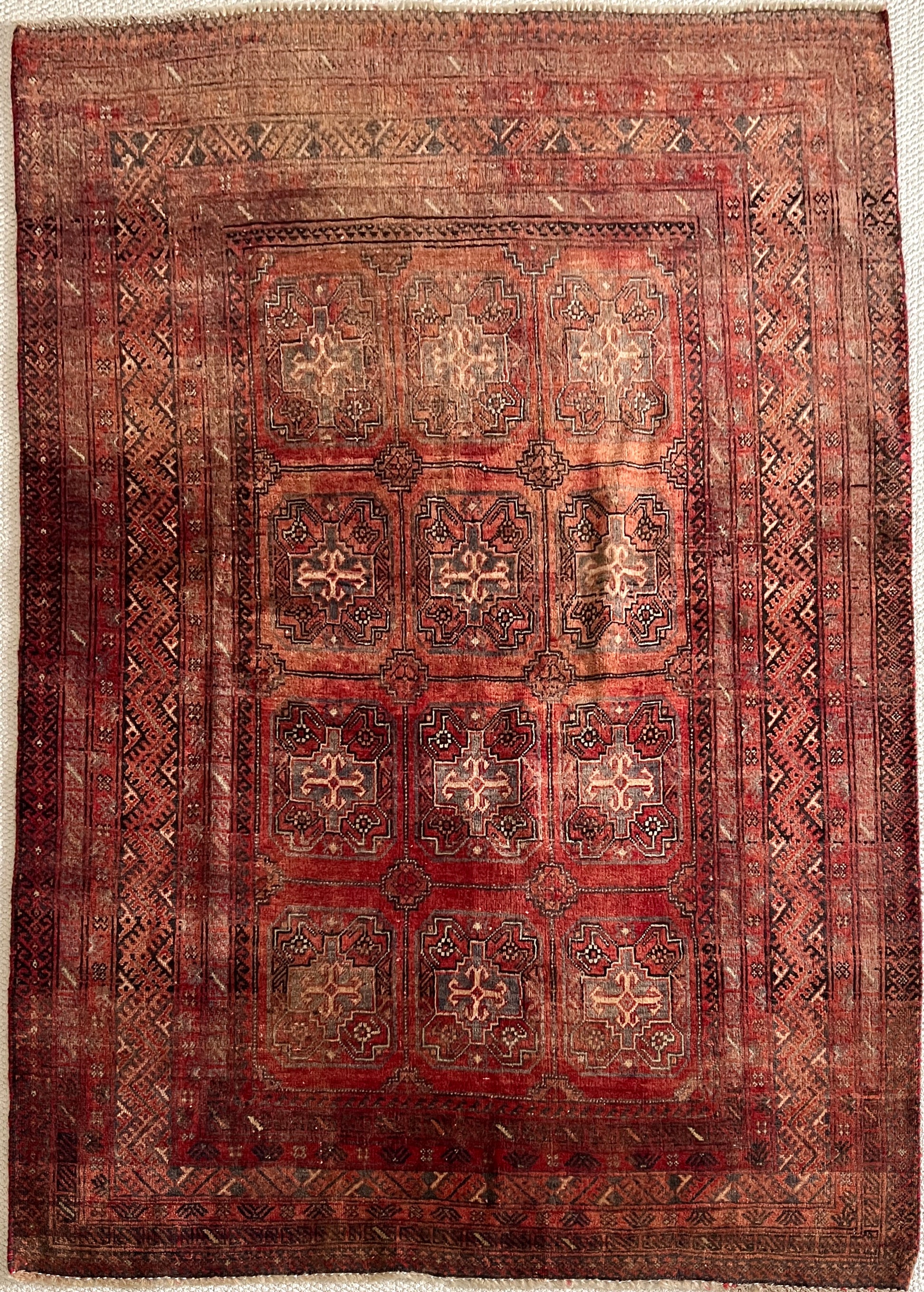 Vintage Persian Turkoman wool area rug, 4x6, full image in full light with varying shades of red and rust in a geometric pattern with cream, charcoal and dark brown accents.