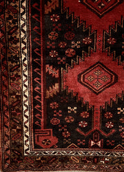 Vintage Persian tribal Heriz hand-knotted wool runner, 3x10. corner detail of geometric patterns in shades of red, dark brown and a geometric decorative border in brown, rust and cream.
