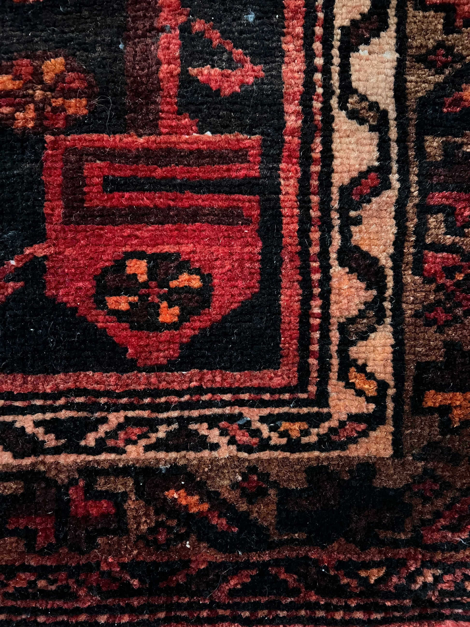 vintage heriz wool runner close up of knotting in shades of red, cream and brown.