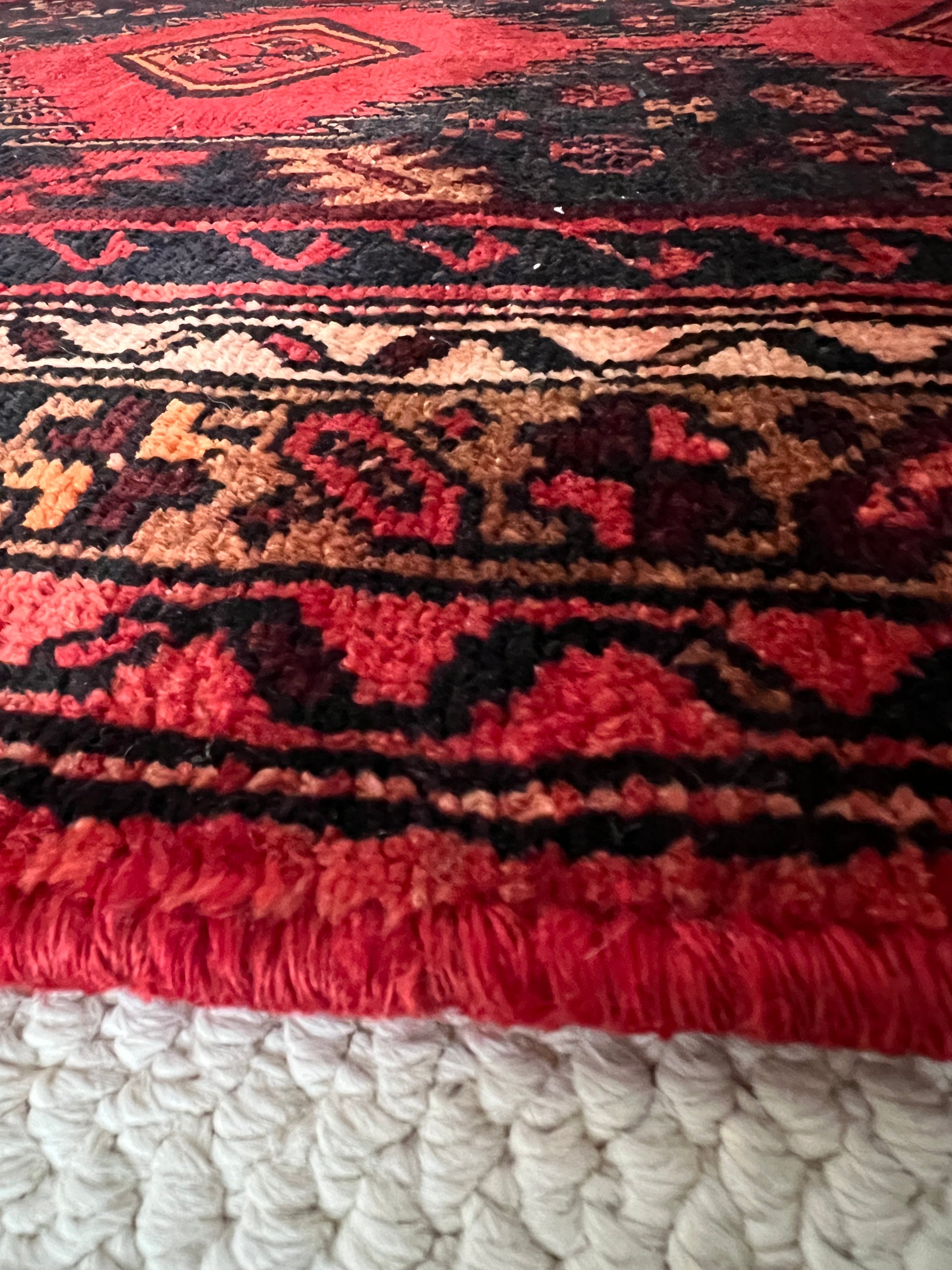 Vintage tribal runner detail of hand woven edge and border with geometric pattern in shades of red, brown and cream.