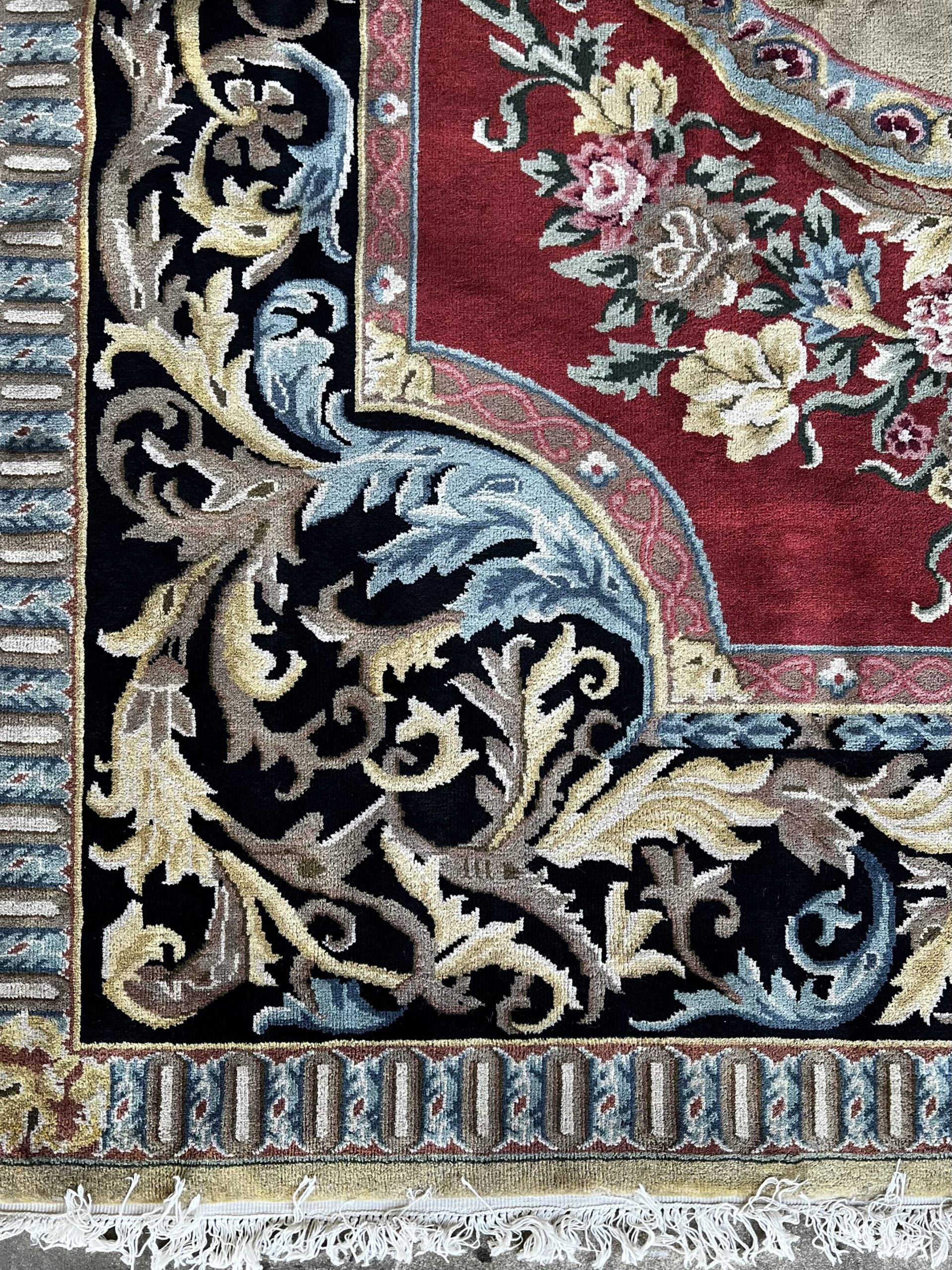 Vintage Indo-Aubusson large wool rug, hand-knotted in India, corner detail of a black border dotted with pale blue, pale pink, and very pale shades of buttery gold against a red ground.