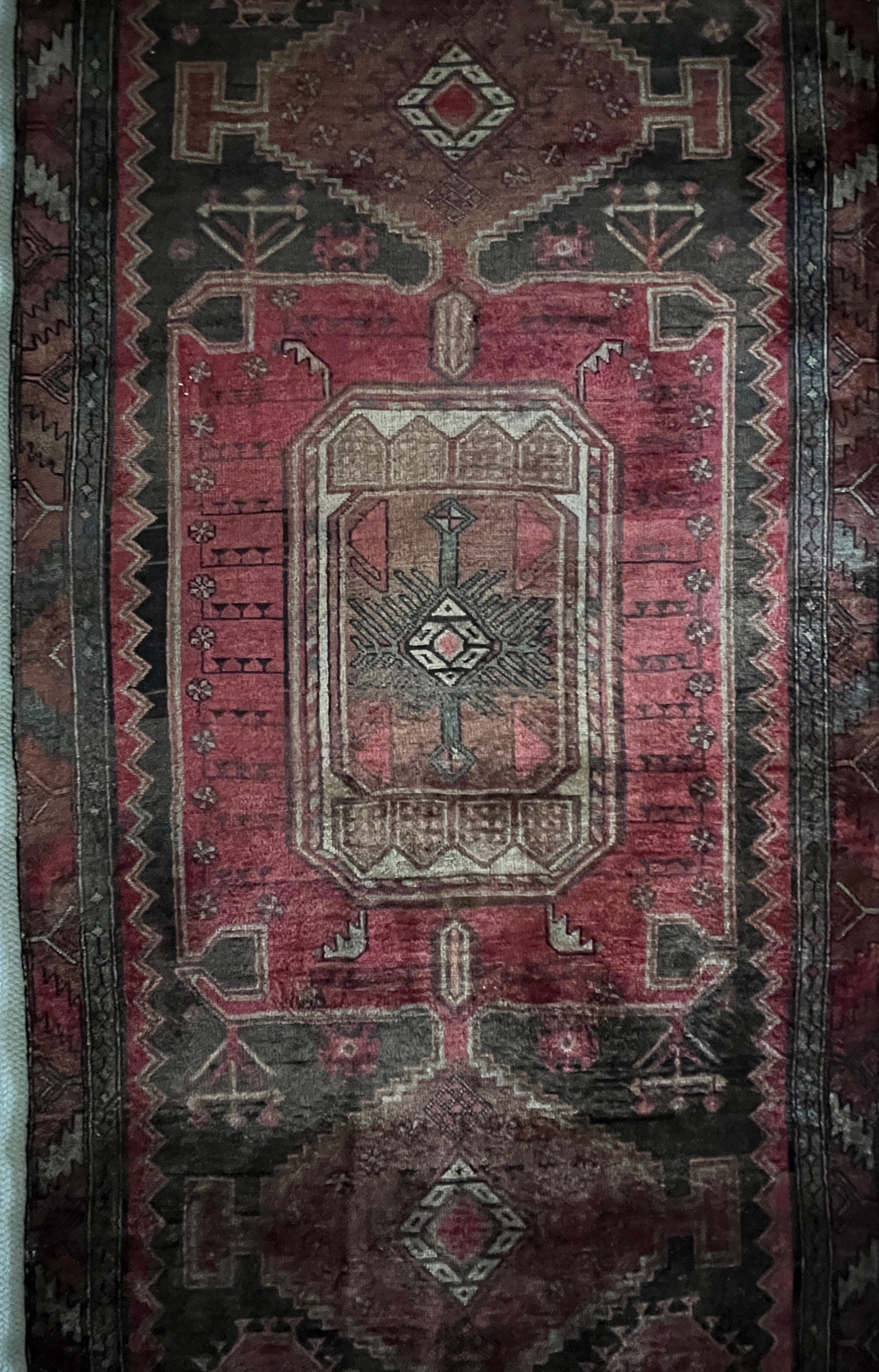 vintage hand-knotted Persian Hamadan wool area rug in muted shades of deep ruby, rust, and brown, set against a black ground with subtle teal accents. 