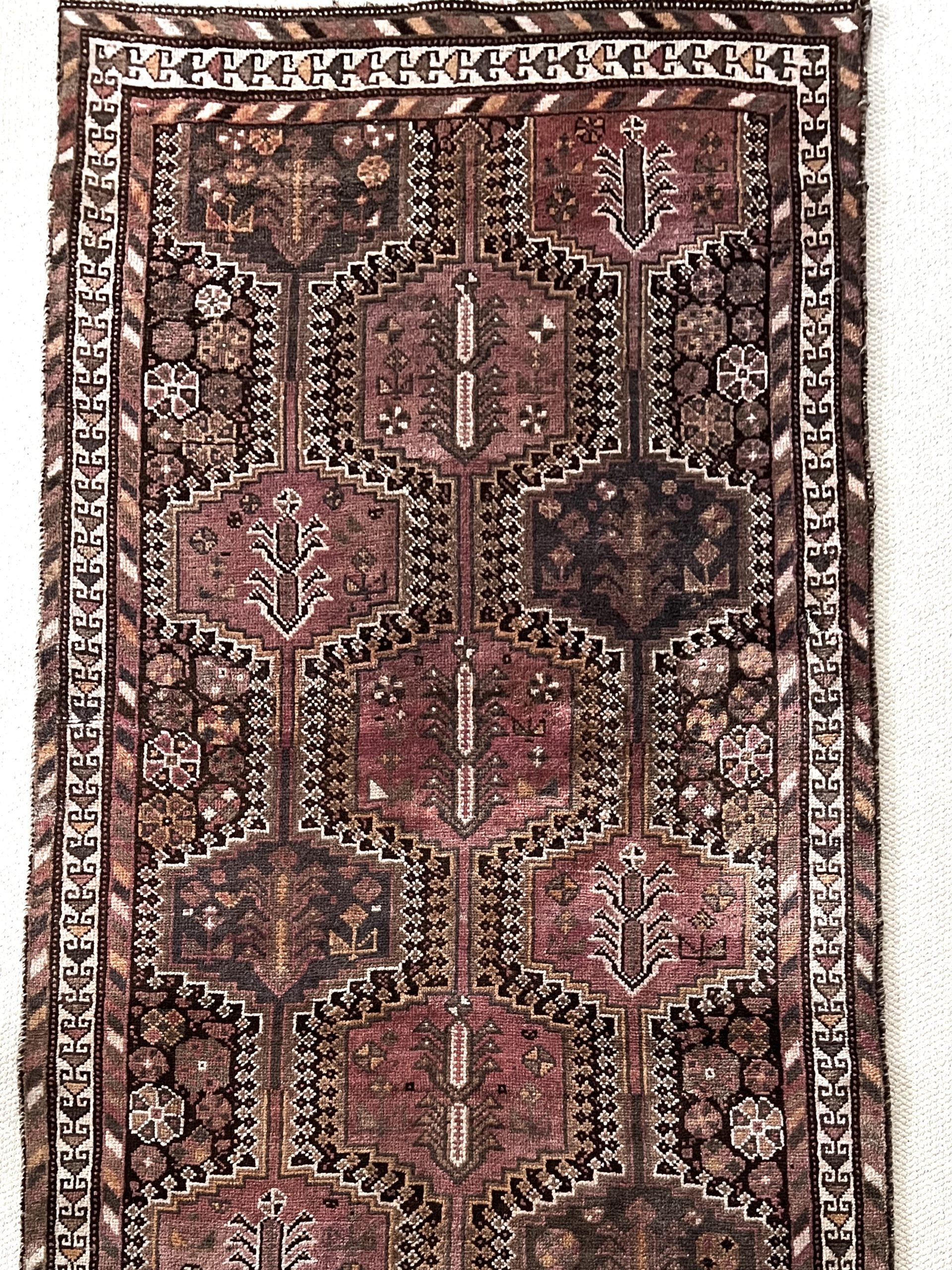 Vintage Persian Baluch rug pillow in warm shades of salmon pink, brown, tan and gold accents in a geometric pattern. 